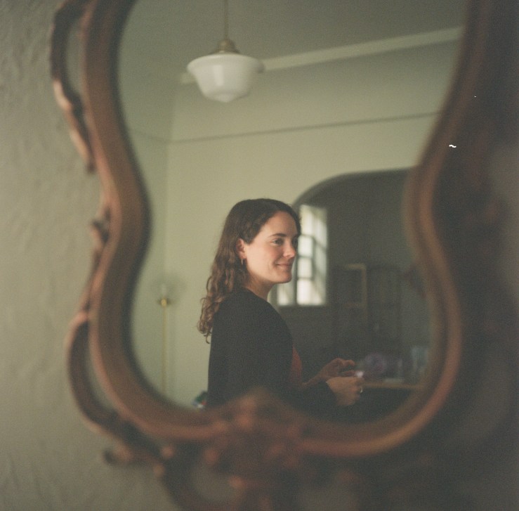 Photo of Emma Aylor in profile, reflected in a mirror.